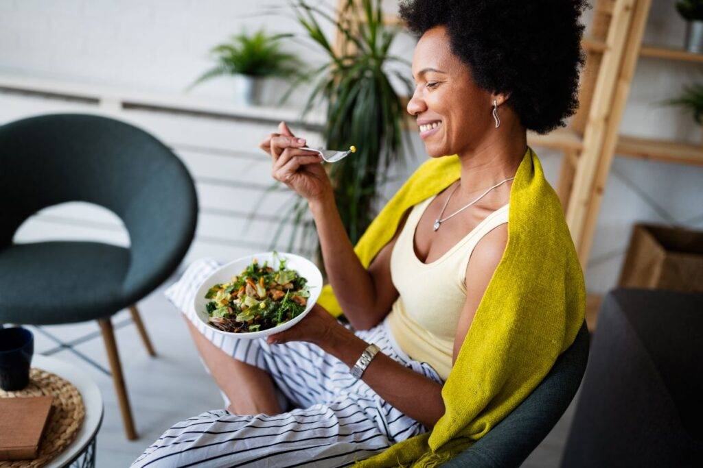 frau isst eine gesunde salatschuessel in einem modernen ambiente in koeln und laechelt zufrieden