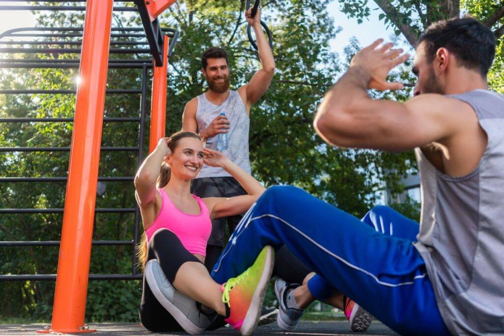 gruppe von freunden macht ein intensives workout an calisthenics-geraeten in einem sonnigen park in koeln