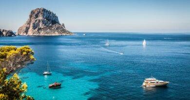 Türkisblaues Meer mit Segelbooten und luxuriöser Yacht vor der Küste Ibizas, im Hintergrund der imposante Felsen Es Vedrà – idealer Ort für Beach Restaurants Ibiza.